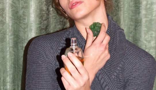 Young woman spraying perfume on neck